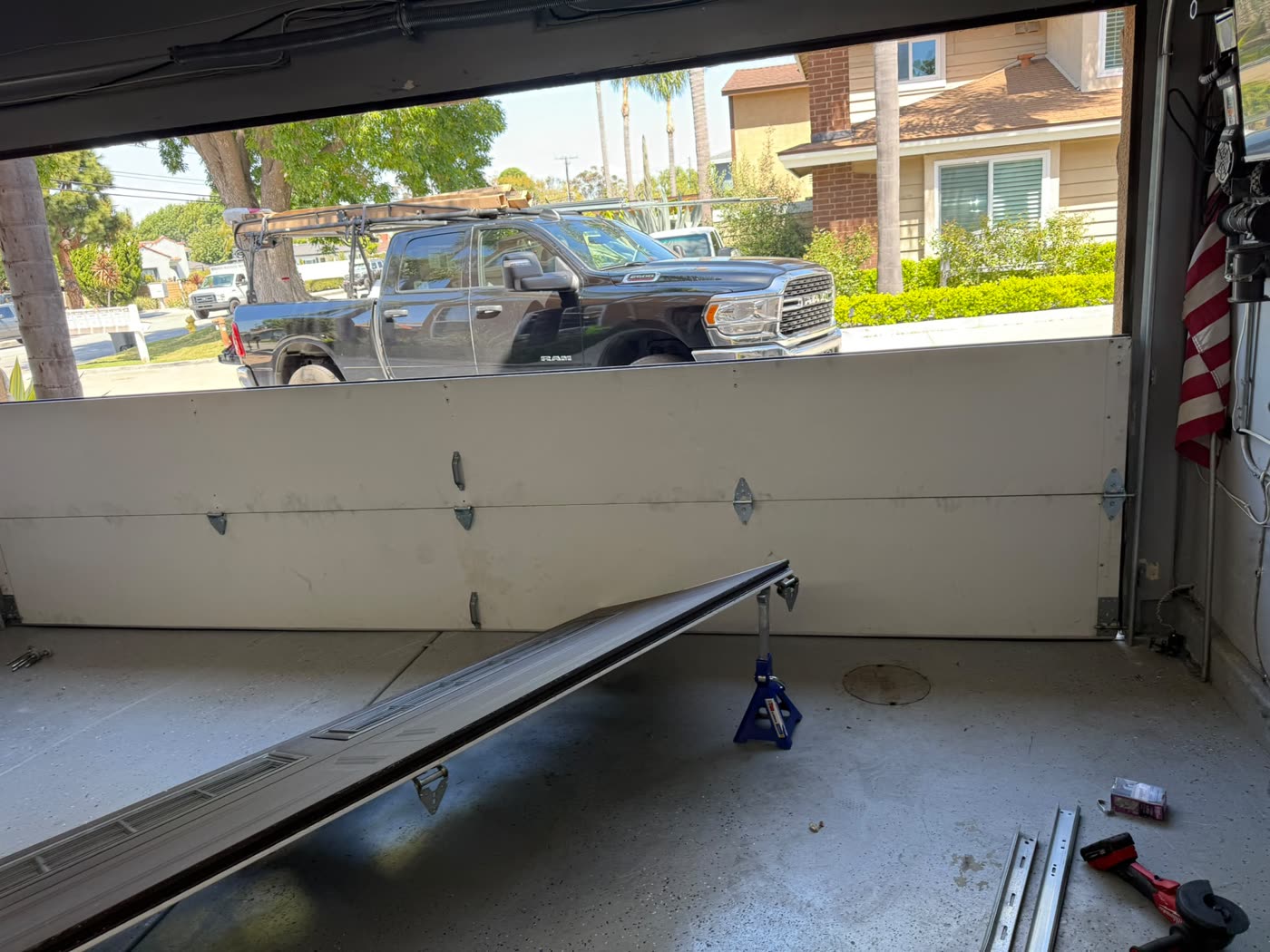 Garage door swap in progress — sections on jack stands and the truck loaded outside