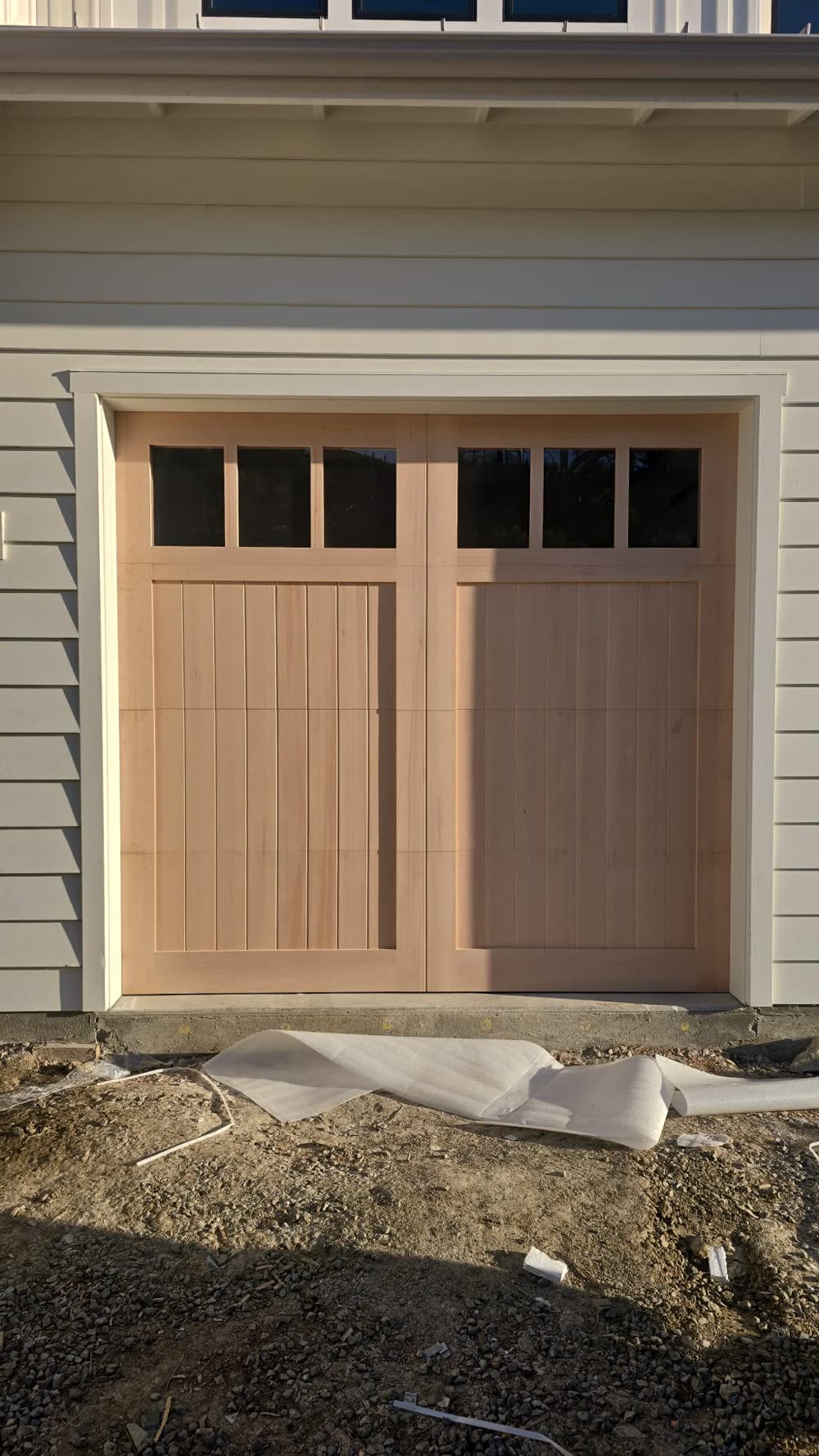 New cedar carriage-house garage door installed on a coastal-style home