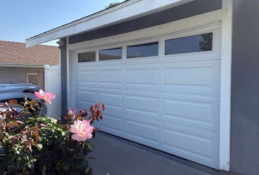 Classic white long-panel garage door with windows, freshly installed