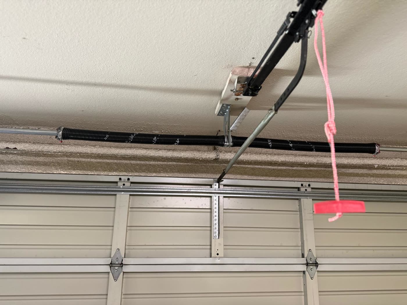 New torsion spring wound, set, and safety-tagged above a garage door