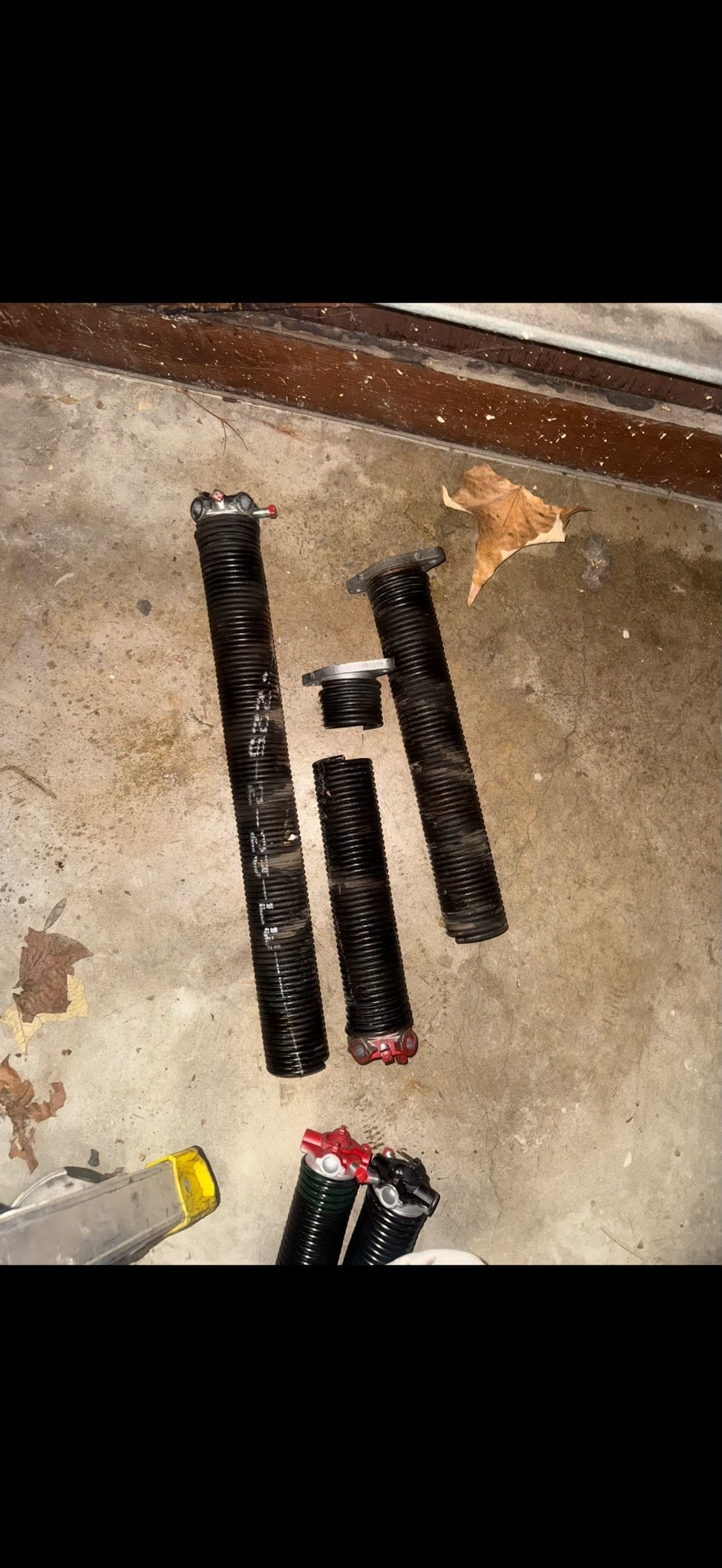 Old worn torsion springs removed from a garage door, laid on the floor
