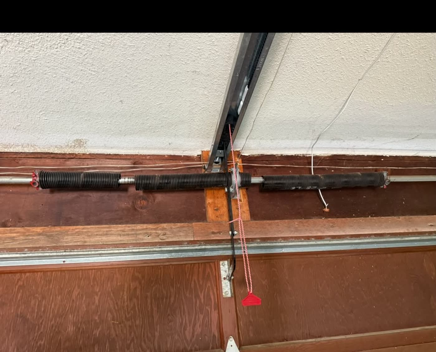 Worn torsion springs on a wooden garage door, before replacement