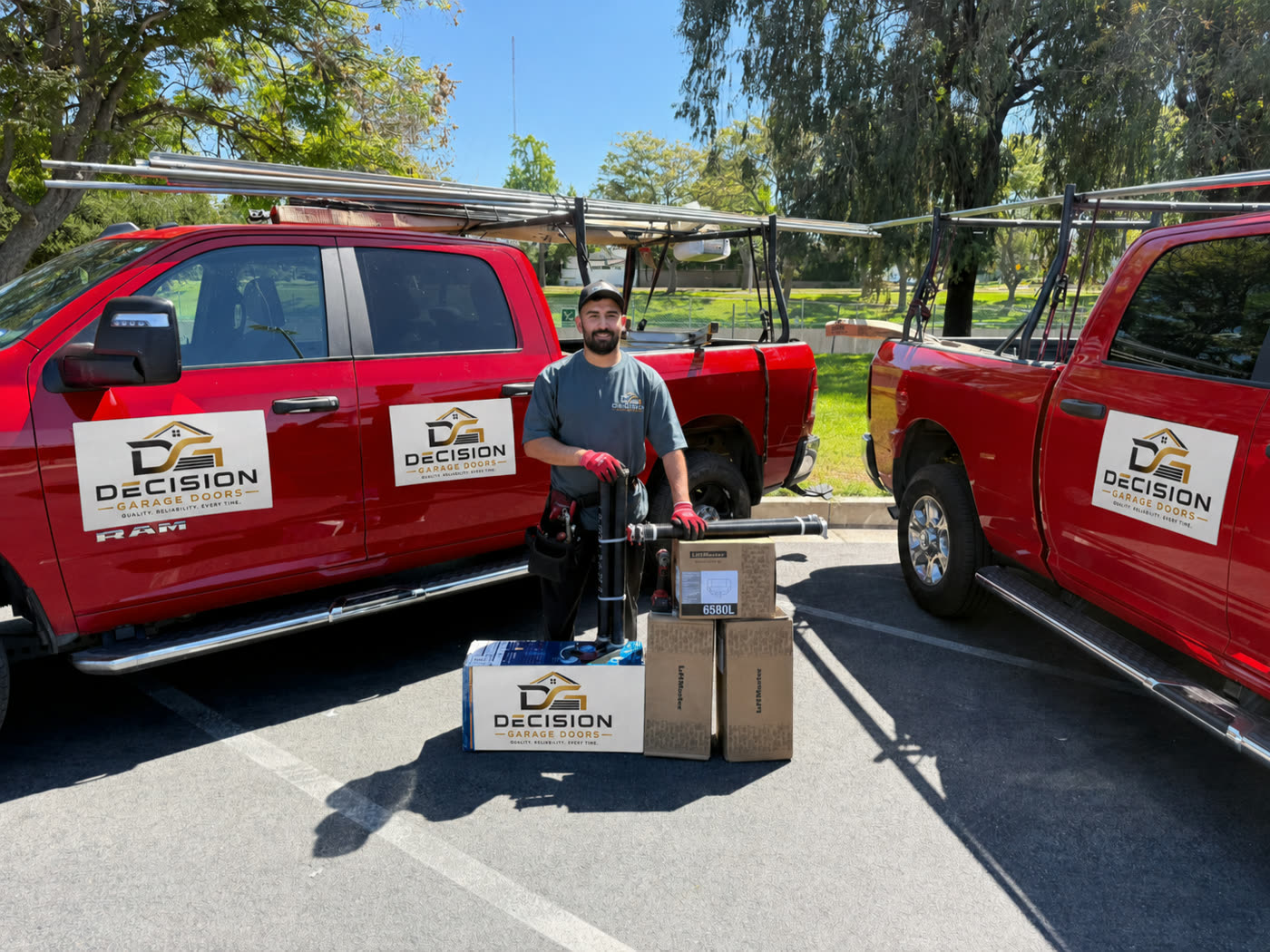 Decision Garage Doors technician standing between two fully stocked company trucks with LiftMaster openers and spring kits